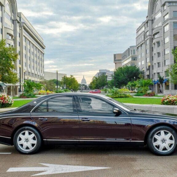 Luxury sedan parked in urban plaza with gardens